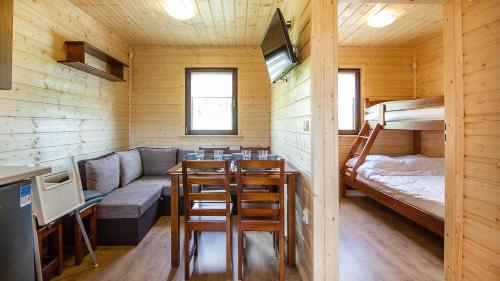 a room with a couch and a table and a bunk bed at Sielankowe Domki in Rusinowo