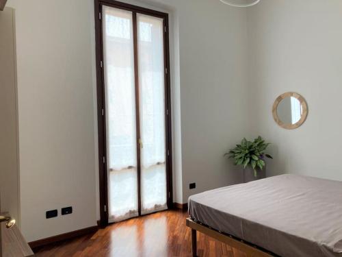 クレモナにあるAppartamento Danteのベッドルーム1室(ベッド1台付)、大きなスライド式ガラスドアが備わります。