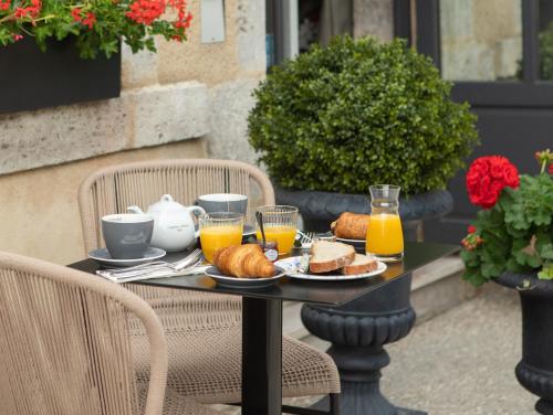 a table with a breakfast of bread and orange juice at Relais de la Loire in Montlivault