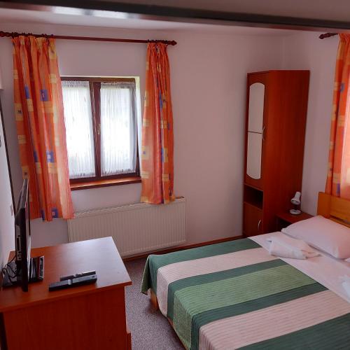a bedroom with a bed and a desk and two windows at house Anna in Plitvička Jezera
