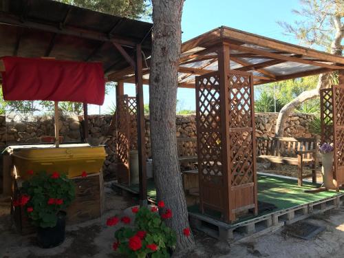 a wooden gazebo with a tree and flowers at Villaggio La Roccia camping in Lampedusa