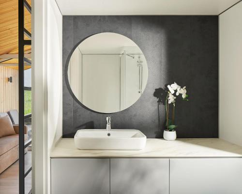 ein Badezimmer mit einem weißen Waschbecken und einem Spiegel in der Unterkunft Modernes Tiny House -neu 2021- in Uigendorf