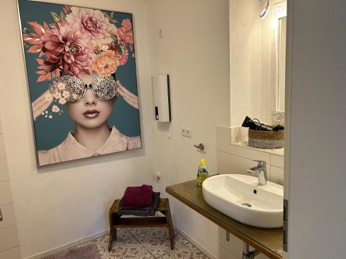 a bathroom with a sink and a painting of a woman at Ferienhaus Maria in Walsdorf