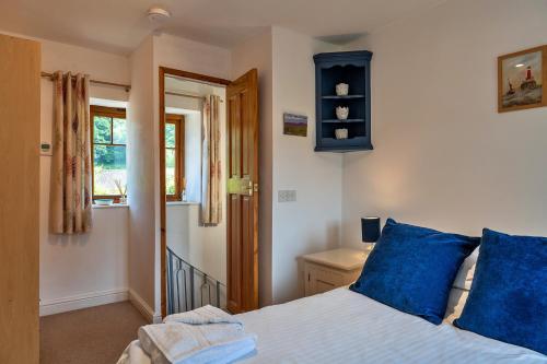 a bedroom with a bed with blue pillows and a window at Finest Retreats - Bamboo Cottage in Timberscombe