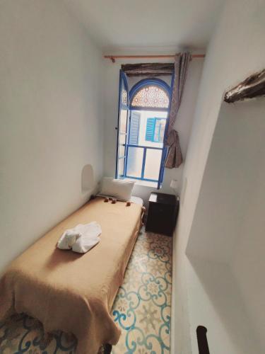 a small room with a bed and a window at Riad AYLAL in Essaouira