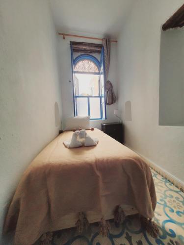 a bedroom with a large bed with a window at Riad AYLAL in Essaouira
