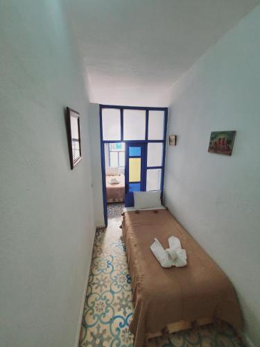 a room with a bed in a room with a window at Riad AYLAL in Essaouira