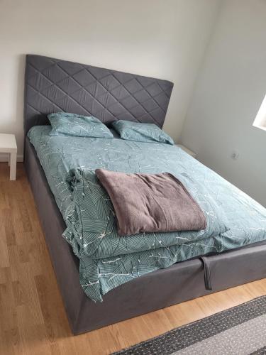 a bed with a gray headboard and pillows on it at Apartman Stan شقة in Plav