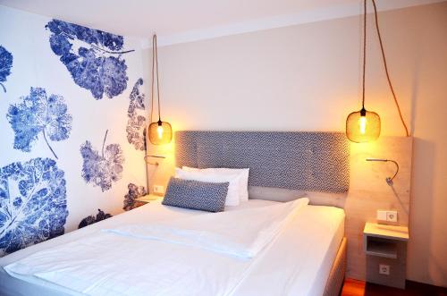 a bedroom with a white bed with two lights at Safranberg Hotel & Sauna in Ulm