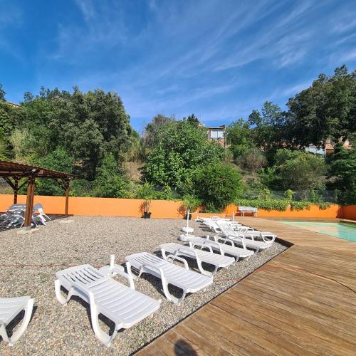 a row of white lounge chairs next to a pool at Entre mer et montagne in Le Boulou