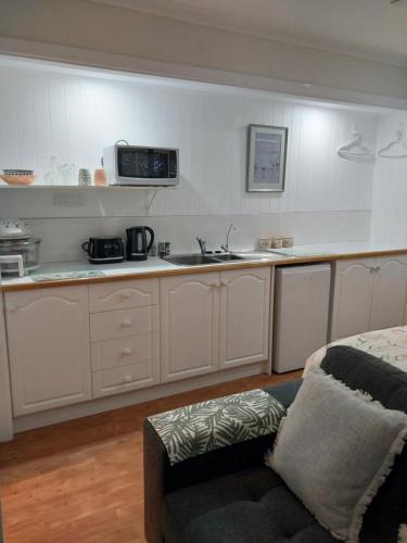 a kitchen with white cabinets and a couch in a room at The Treasure Box in Esperance