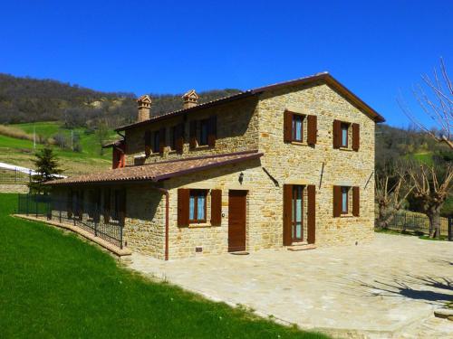 a large brick house with a green field in front at Country House Le Grazie in Serra San Quirico