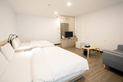 a white bedroom with a bed and a couch at 池上大地飯店 in Chishang