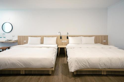 two beds in a room with a desk and a mirror at 池上大地飯店 in Chishang
