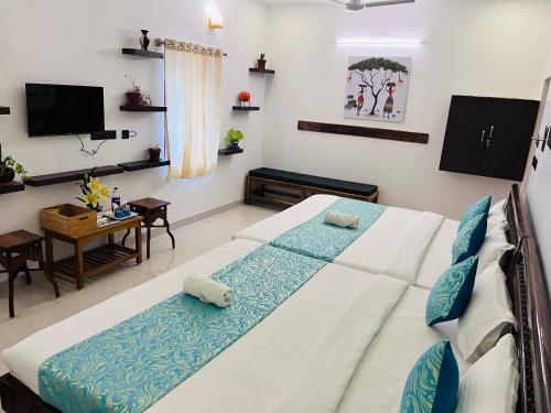 a bedroom with two beds and a table and a television at THE LUXE HOTEL, ECR ROAD, NEAR Serenity Beach, Pondicherry - JR Groups in Puducherry