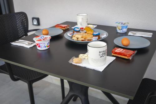 RAFKON Luxury Apartments - Myrina في ميرينا: طاولة سوداء مع أطباق من الطعام عليها