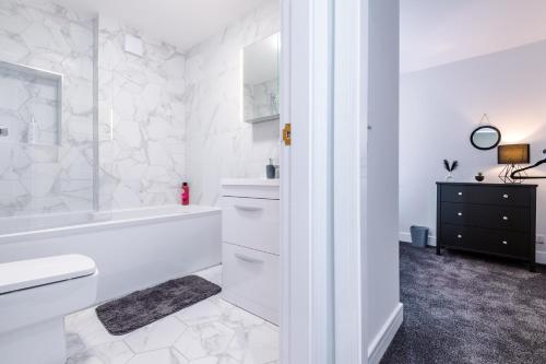 a white bathroom with a tub and a sink at 4 bed property, Bolton , Manchester in Egerton