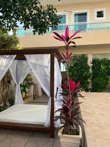 a bed with a canopy and a plant on a patio at Suítes Brandi in Arraial do Cabo