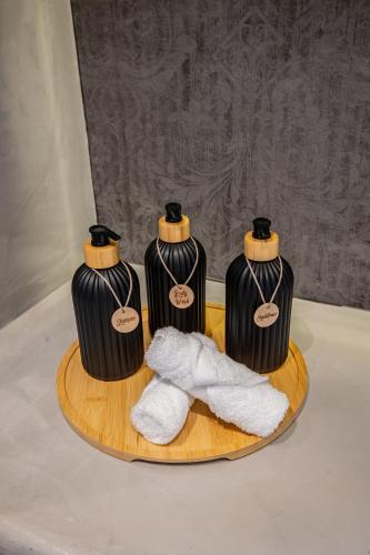 three black and white bottles on a wooden tray with towels at Bonsai Luxury Suites in Karterados