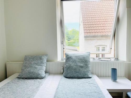 a bed with two pillows sitting in front of a window at Scandinavian Apartment Hotel -Lunden 2- Central 2 room apartment in Horsens