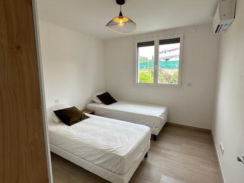 two beds in a small room with a window at Alivu - Appartement Moderne Avec Terrasse in Cargèse