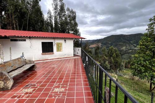 a house with a balcony with a brick walkway at Cabaña en la montaña de 3 Habitaciones in Sutatausa