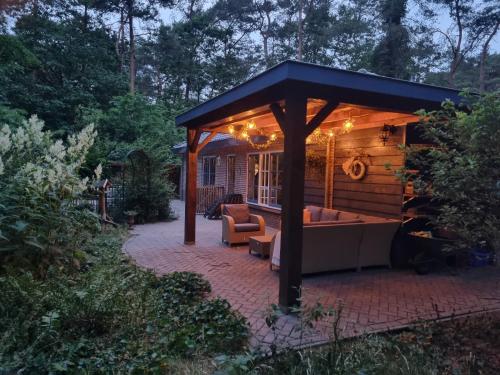 a gazebo with a couch on a brick patio at Holiday home bos en heide in Otterlo