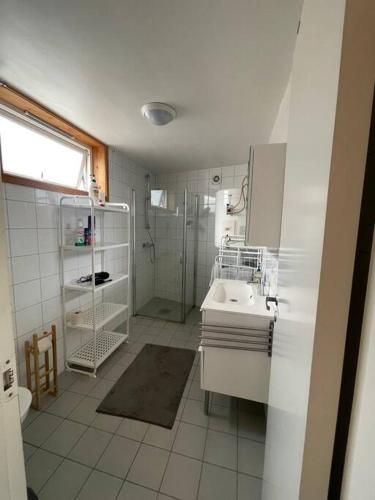 a white bathroom with a shower and a sink at City Center Stylish Loft in Trondheim