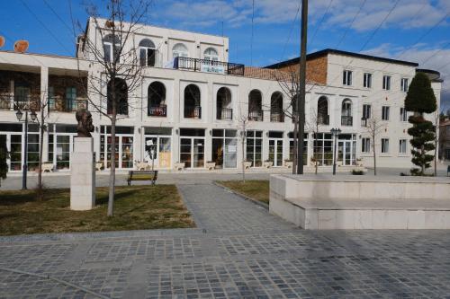 a large white building with a park in front of it at As e vogël, As e madhe in Ersekë