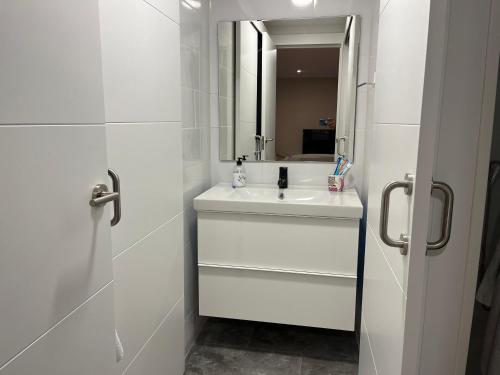 a white bathroom with a sink and a mirror at apartamento luanco playa in Luanco
