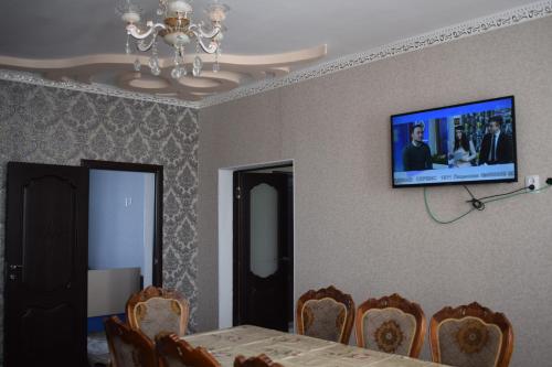 a dining room with a table and a tv on the wall at Kyzart Guesthouse in Bagysh