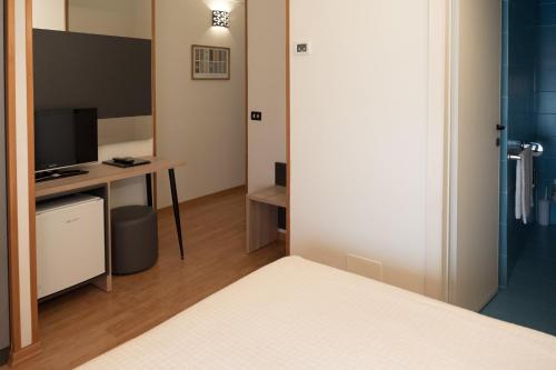 a room with a bed and a desk and a television at Hotel St Gregory Park in Rimini