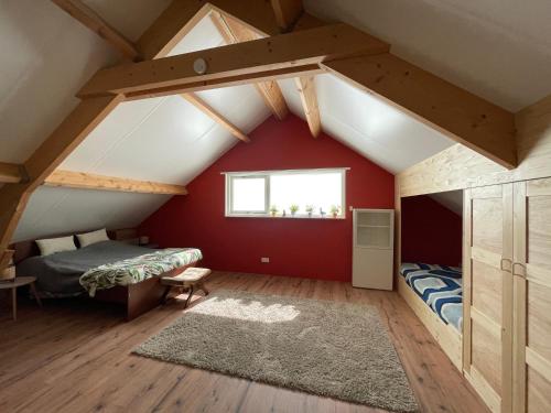 een slaapkamer op zolder met rode muren en een raam bij Het Riethuis in Holthone