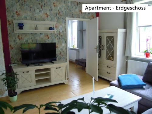 a living room with a flat screen tv on a cabinet at Ferienwohnung Wolfsholz in Wernigerode