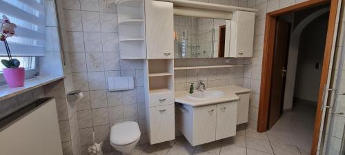 een witte badkamer met een wastafel en een toilet bij Moderne120qm Ferienwohnung in ruhiger Lage Heusweiler - Saarland in Heusweiler