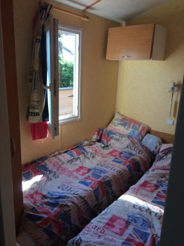 a small bedroom with a bed and a window at Mobilhome camping les petits écureuils 4 étoiles Biscarrosse in Biscarrosse