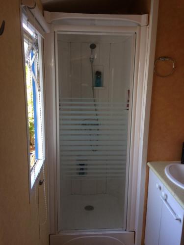 a shower in a bathroom next to a sink at Mobilhome camping les petits écureuils 4 étoiles Biscarrosse in Biscarrosse