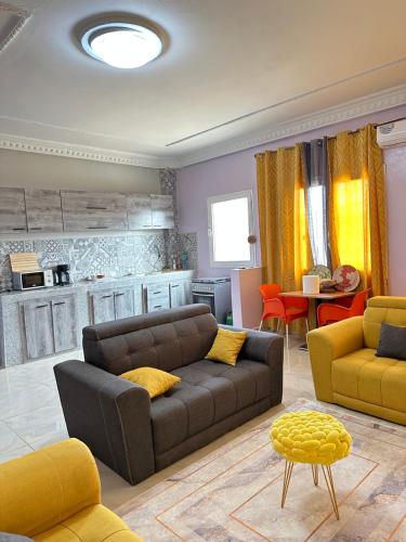 - un salon avec un canapé brun et des fauteuils jaunes dans l'établissement Résidences PRIMIS Thiès - appartements et chambres, à Thiès