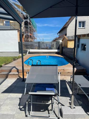 a chair and an umbrella next to a swimming pool at #3 bequemes Zimmer mit Pool und Garten in Memmingen