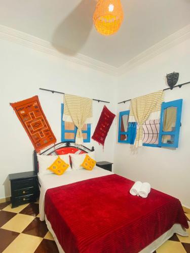 a bedroom with a bed with a red bedspread at Rayane Guest House in Taghazout