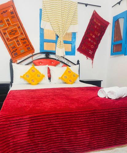 a bedroom with a red bed with yellow and white pillows at Rayane Guest House in Taghazout