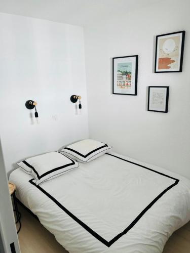une chambre avec un lit blanc avec trois tableaux au mur dans l'établissement Très joli Appartement 2P au Beach Résidence Trouville- Piscine & vue port, à Trouville-sur-Mer
