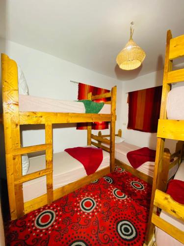 a room with two bunk beds and a red carpet at Rayane Guest House in Taghazout