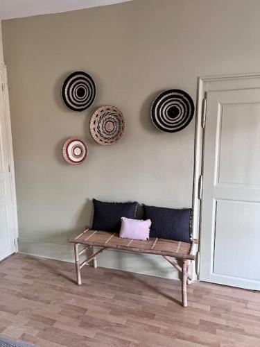 a wooden bench sitting in a room with plates on the wall at Appartement de caractère in Épinal