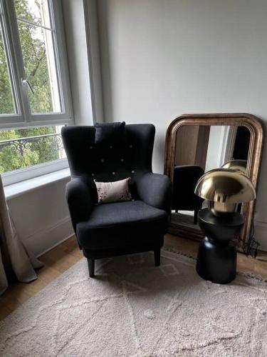a chair and a lamp in a room with a mirror at Appartement de caractère in Épinal