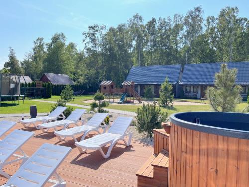 a row of lounge chairs on a deck with a playground at Domki Zalesie in Jarosławiec