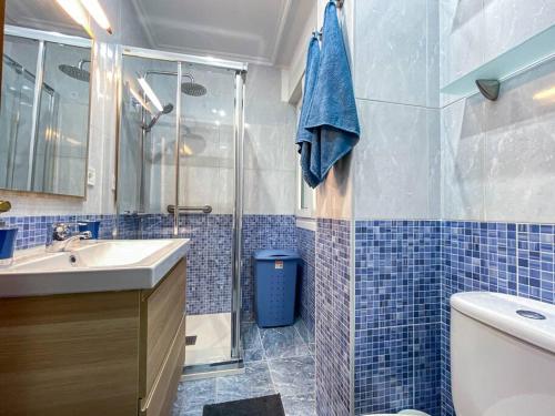 a blue tiled bathroom with a sink and a shower at Apartamento coqueto gran Bilbao in Basauri