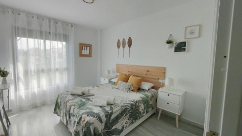 a white bedroom with a bed and a window at Luxury Apartment Bajondillo Beachfront in Torremolinos