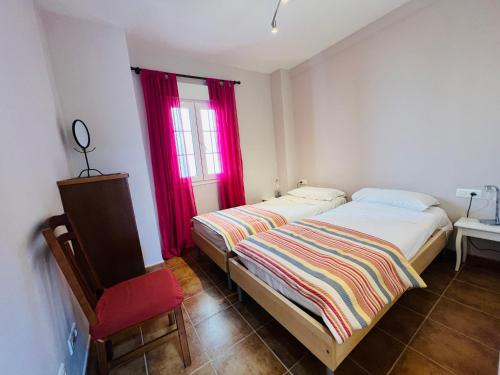 a bedroom with two beds and a window with red curtains at Marina 4 apartment in Huelva