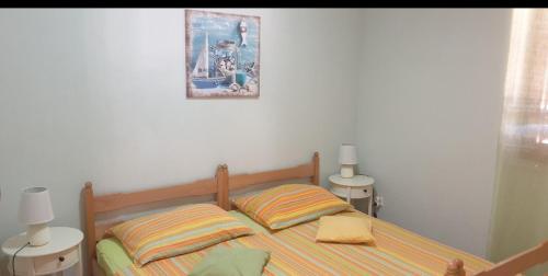 a bed with two pillows and a picture on the wall at Apartmani Kerum in Jelsa